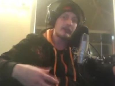 Barney Harris is on a hoodie, wearing a headphone and speaking in the mic.